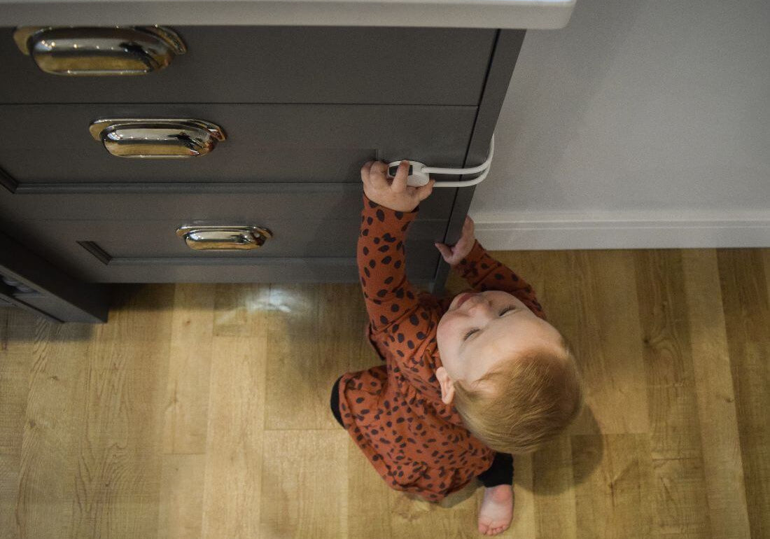 Baby trying to open cupboard with child safety lock
