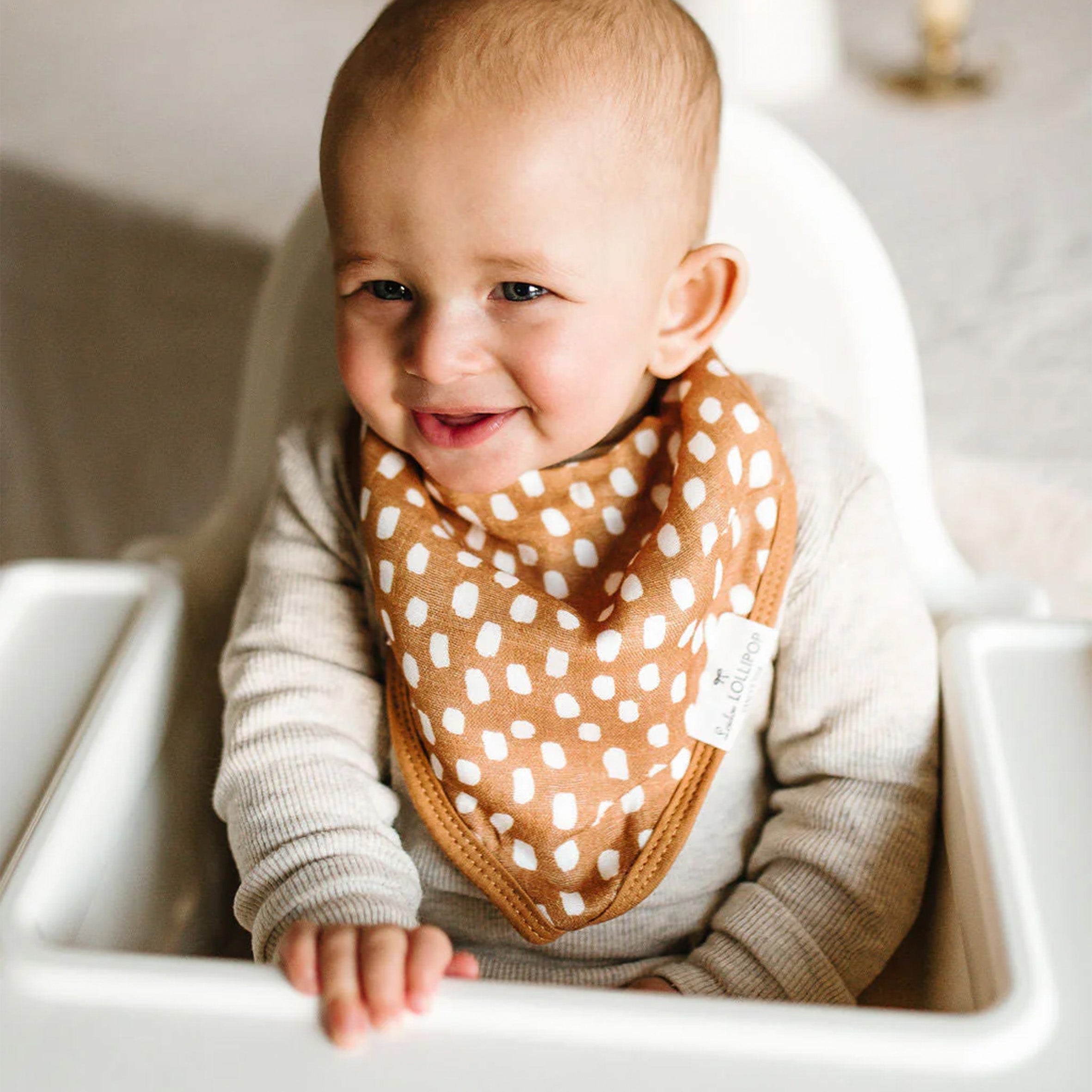 Baby wearing a Bandana Bib, sitting in a high chair
