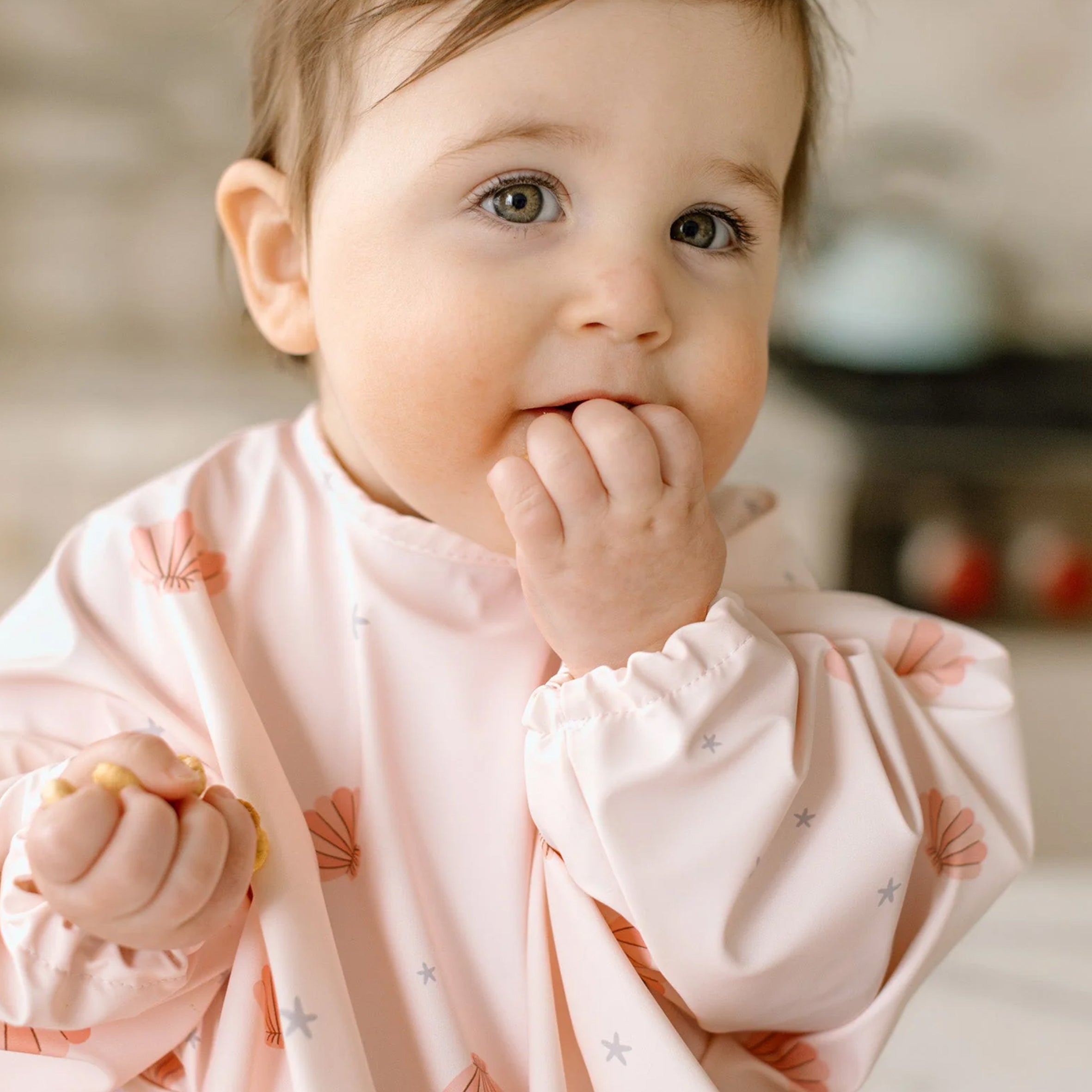 Baby in a Sea Shells Long Sleeve Bib with a soft focus background