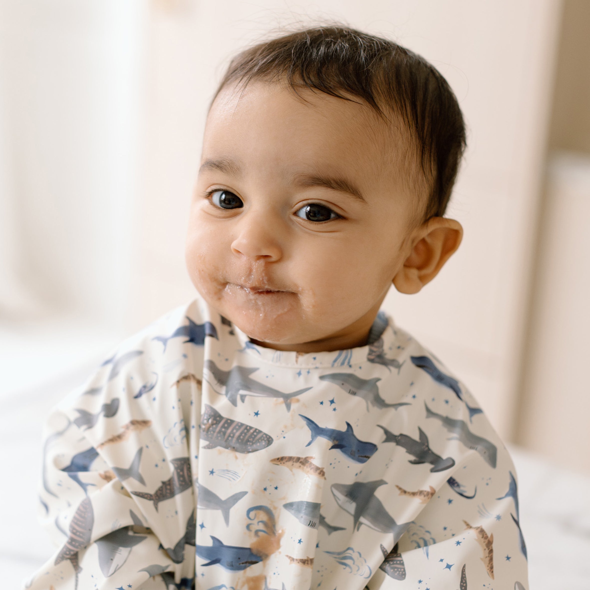 Baby wearing a Smiley Shark Long Sleeve Bib on a neutral background
