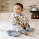 Baby wearing a Smiley Shark Long Sleeve Bib in a kitchen setting