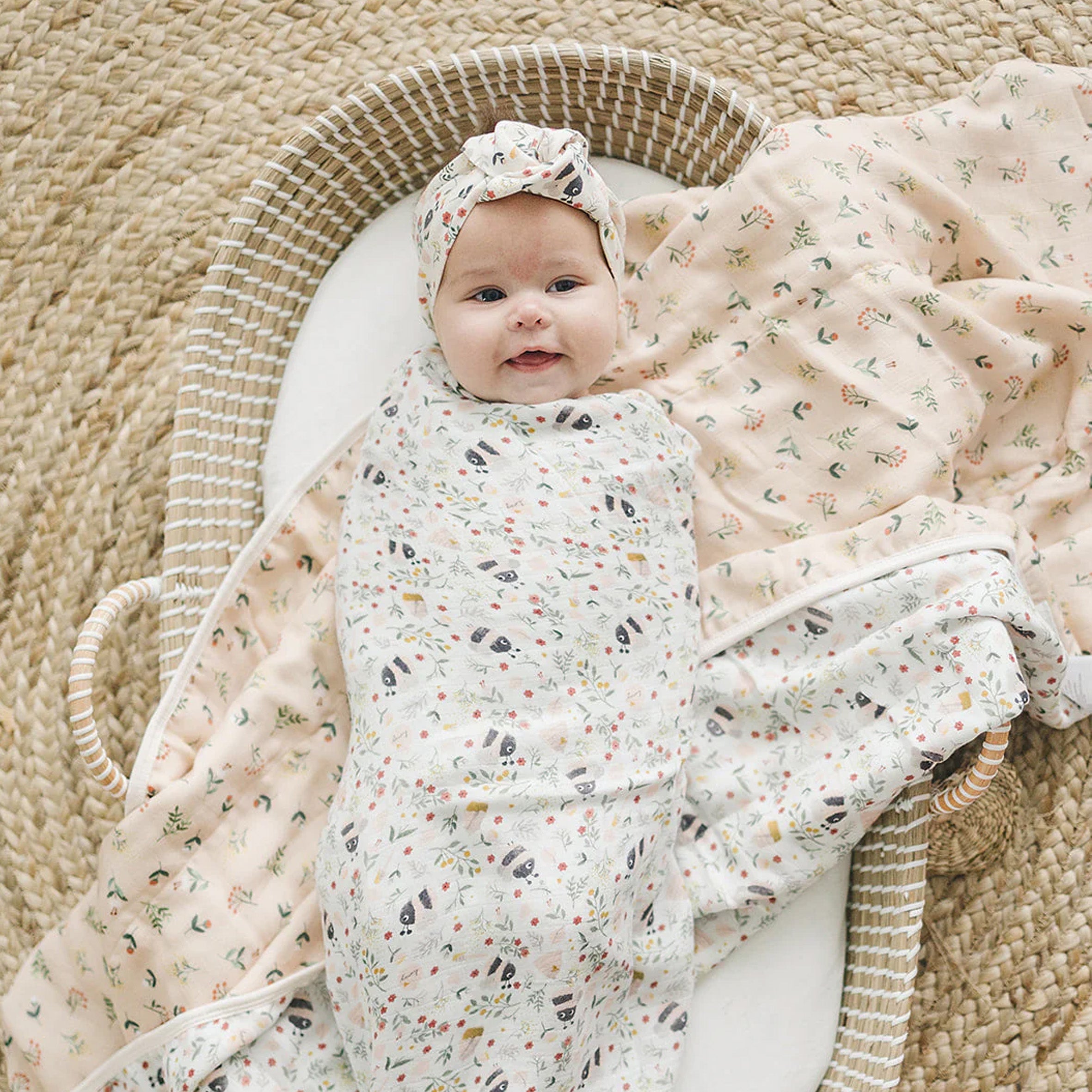 Baby wrapped in a Bumble Bees Muslin Swaddle on a woven basket