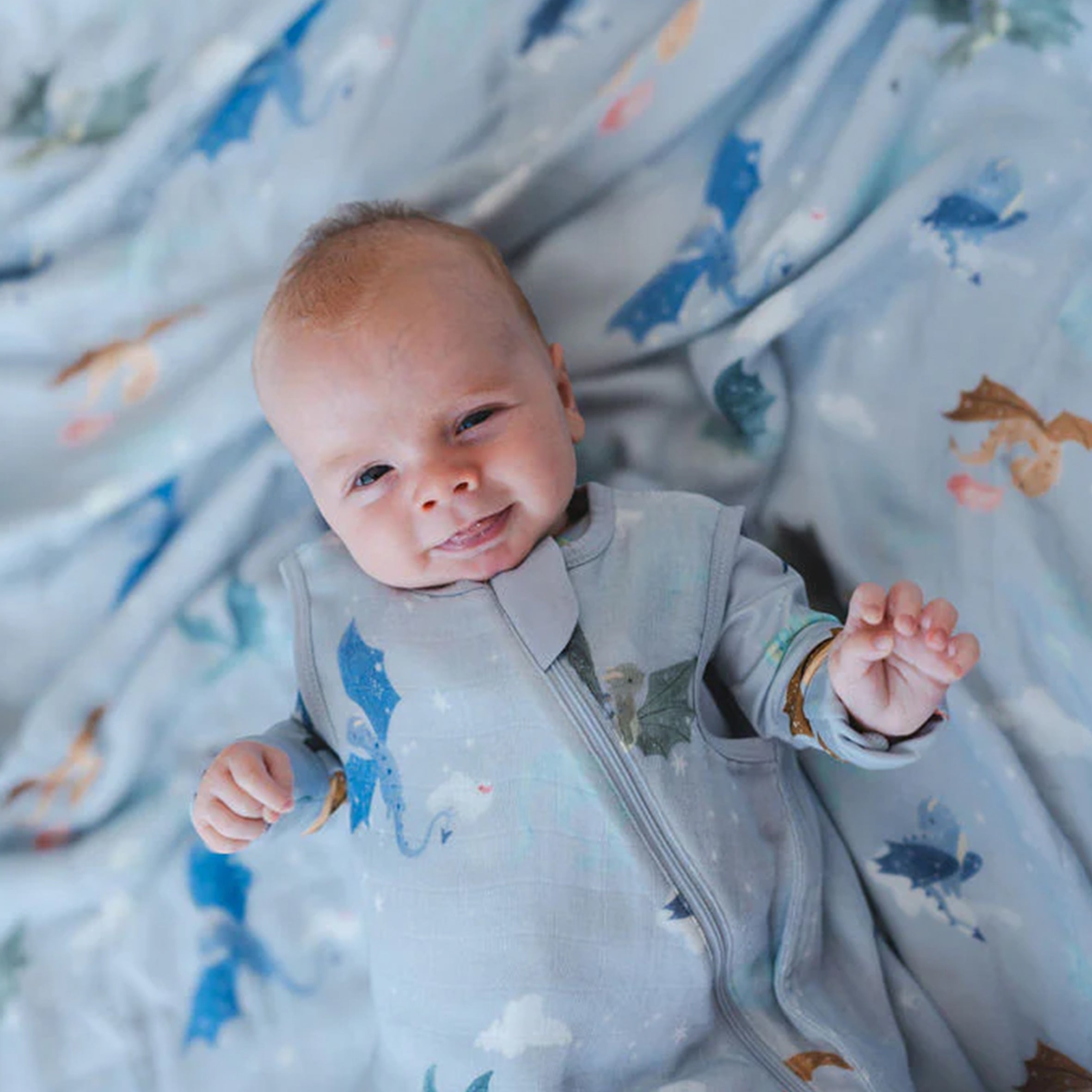 Baby in a Magical Dragons sleeping bag, surrounded by similar patterned fabric