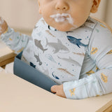 Baby wearing a Shark Silicone bib, sitting in a high chair.