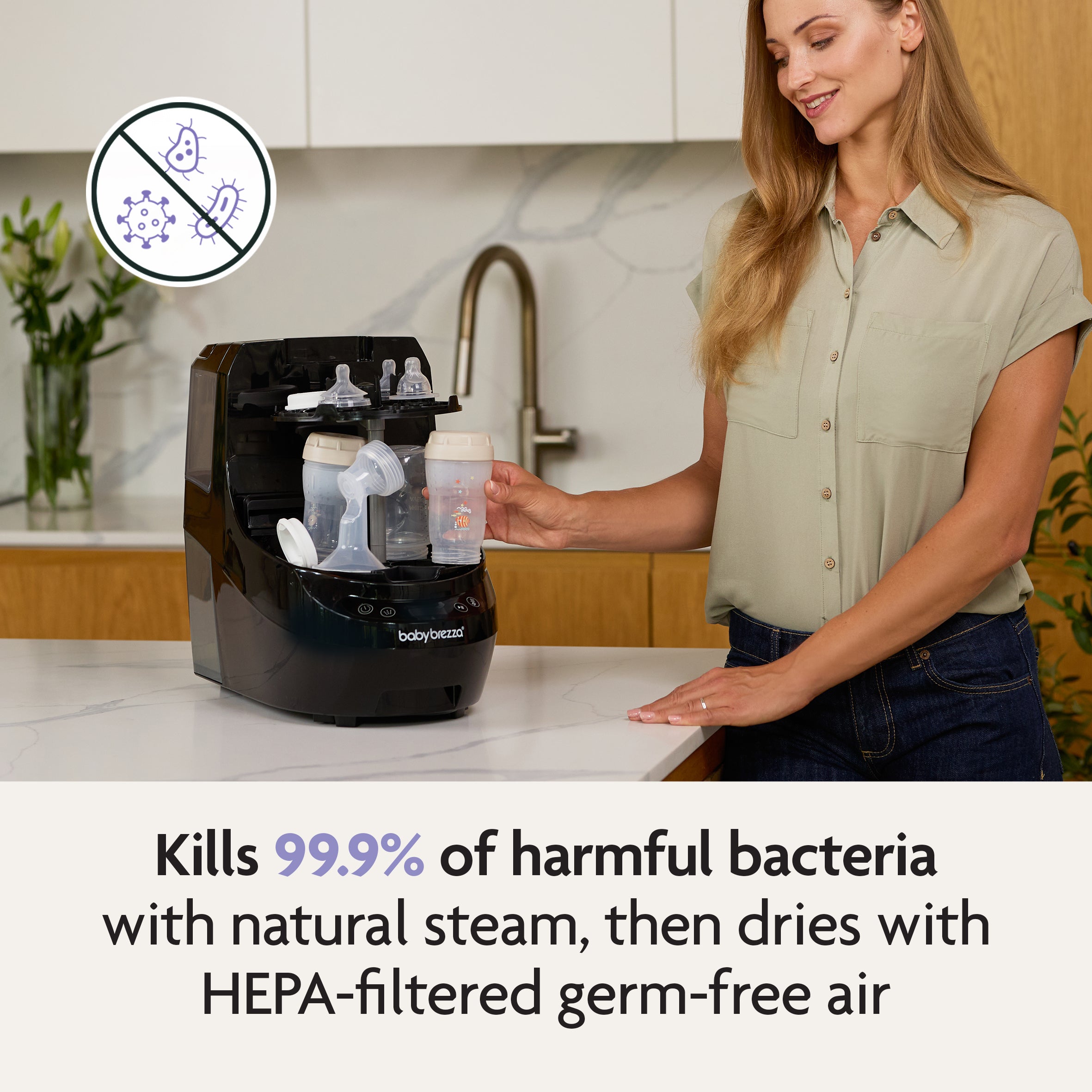 A woman uses the Baby Brezza Bottle Washer Pro® - All Black on her kitchen counter. It kills 99.9% of harmful bacteria with natural steam, dries bottles with HEPA-filtered air, and offers automatic cleaning for peace of mind. Bacteria icon crossed out.