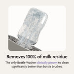 The Baby Brezza Bottle Washer Pro® - All Black cleans a clear baby bottle upside down with water jets. Text: “Removes 100% of milk residue. The only Bottle Washer clinically proven to clean better than bottle brushes.”.