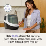 A woman in a striped shirt operates a white Baby Brezza Bottle Washer Pro® on a kitchen counter, with an icon showing germs being crossed out and text stating it kills 99.9% of harmful bacteria with steam and HEPA-filtered air.