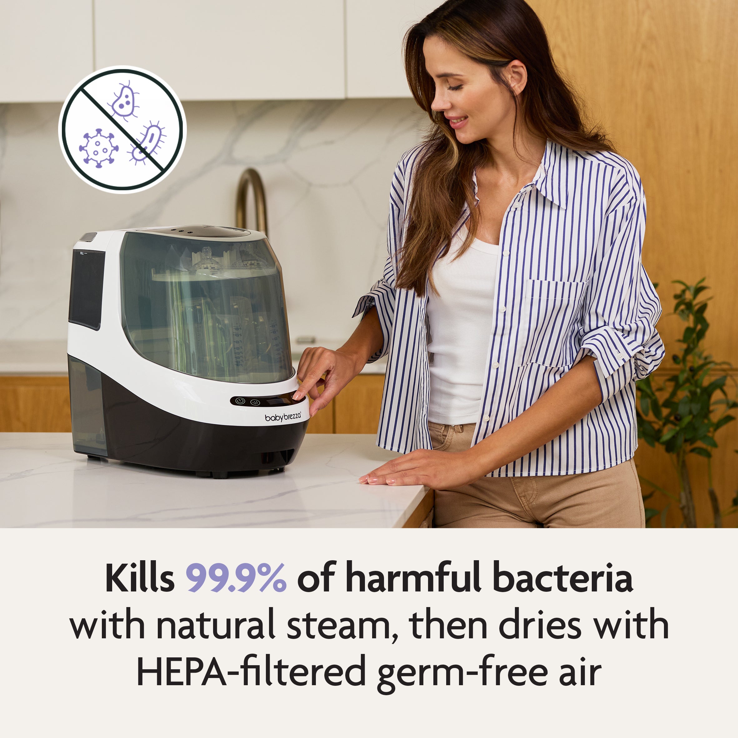A woman in a striped shirt operates a white Baby Brezza Bottle Washer Pro® on a kitchen counter, with an icon showing germs being crossed out and text stating it kills 99.9% of harmful bacteria with steam and HEPA-filtered air.