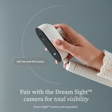 A hand holds a baby monitor camera on an Owlet Dream Sight™ Camera Stand, with a dashed arc indicating 360-degree pan-and-tilt motion and text stating: Pair with the Dream Sight camera for total visibility.