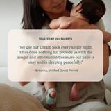 An adult holds a baby wearing a foot monitor, shown alongside a parent’s testimonial and an Owlet Dream Sight™ Camera Stand.
