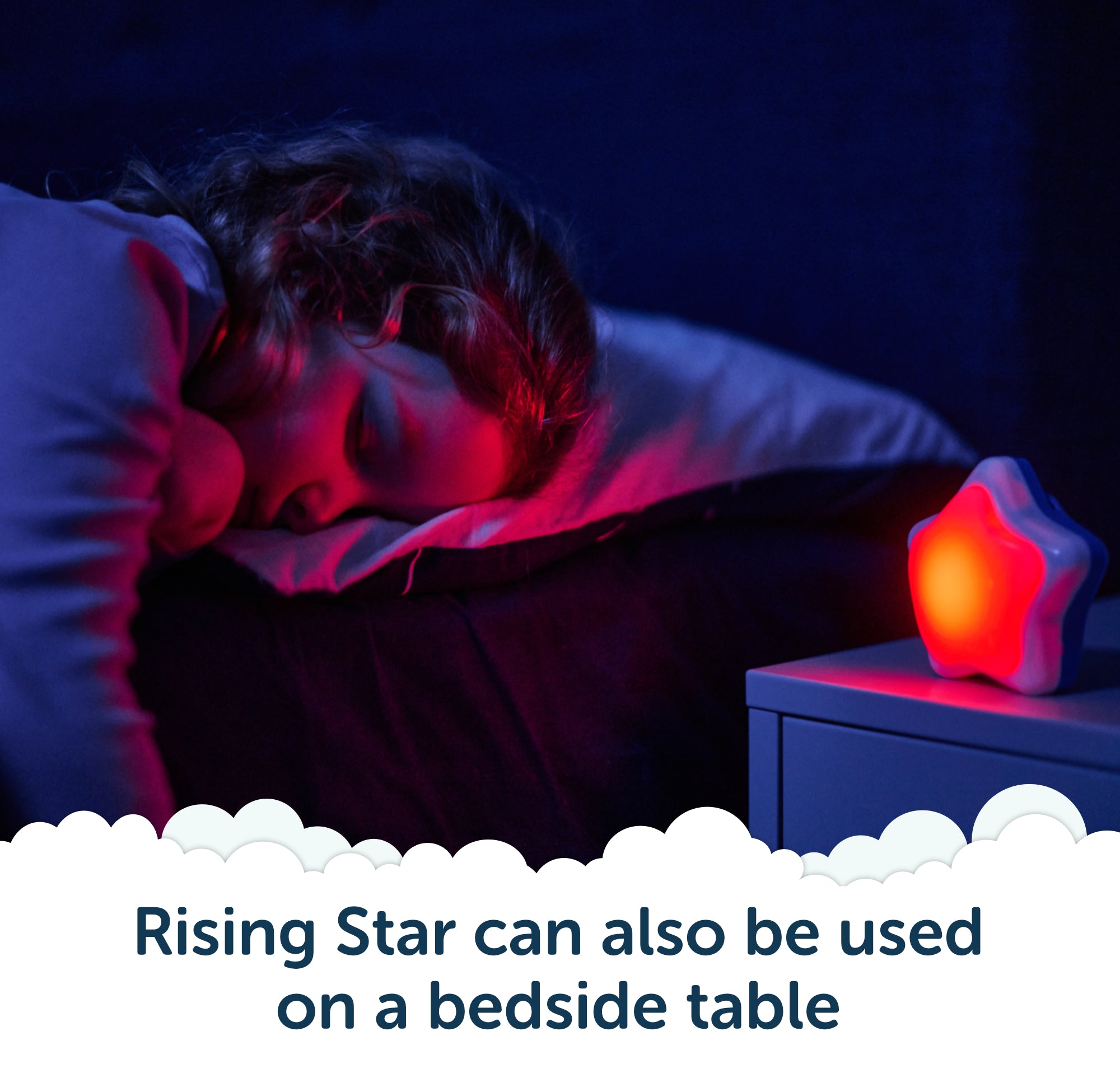 A child sleeps in bed beside a glowing star-shaped night light and Rockit’s Rising Star – The Rewarding Sleep Clock on the bedside table. Text reads, Rising Star can also be used on a bedside table.
